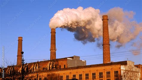 Foto Stock Factory plant puffs smoke stack over blue sky background. Energy generation and air ...