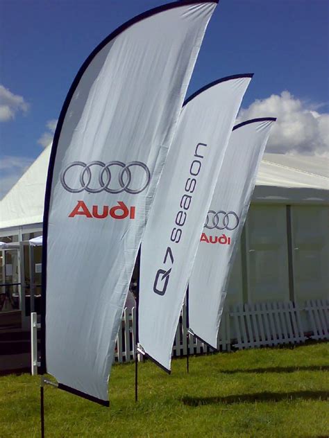 two flags with audi logos on them are in the grass next to a white tent