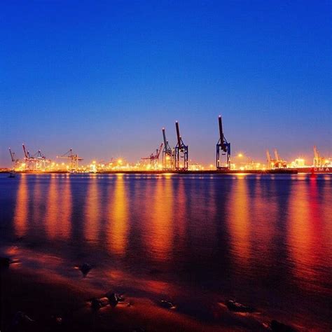 an industrial port at night with lights reflecting off the water and ...