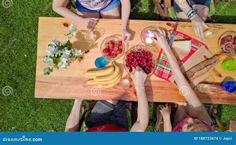 Family and Friends Eating Together Outdoors on Summer Garden Party. Aerial View of Table with ...