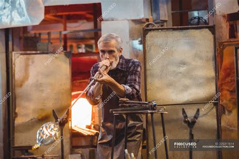 Glassblower shaping a glass on the blowpipe at glassblowing factory — forming, tool - Stock ...