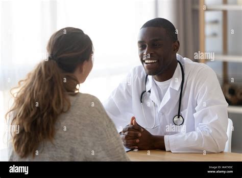 Smiling black male doctor listening female patient at medical meeting Stock Photo - Alamy