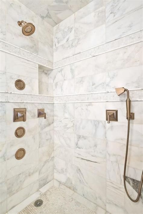 Calcutta gold marble clad walk in shower is accented with white tumbled marble mosaic border ...