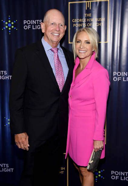 an older man and woman standing next to each other in front of a blue wall