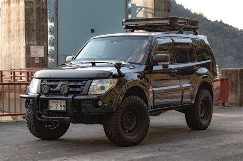 a black four door suv parked in front of a bridge