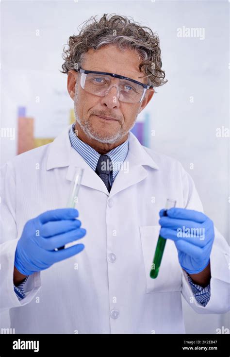 A passion for chemistry. A cropped portrait of a mature scientist holding two test tubes in his ...