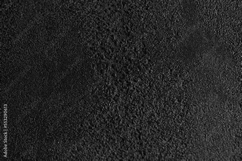 Close up of dark grey, grainy surface for modern, unusual background design. Rough texture of ...