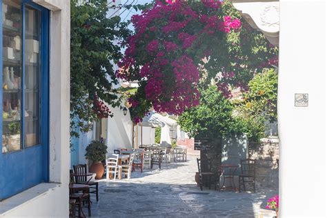 Typical Greek alley on the island Naxos with white-blue buildings, bougainvillea plants ...
