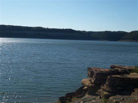 there is a boat that is out on the water near some rocks and trees in ...