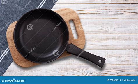 Black Fry Pan and Board with Napkin on Wooden Table. Top View Mockup ...