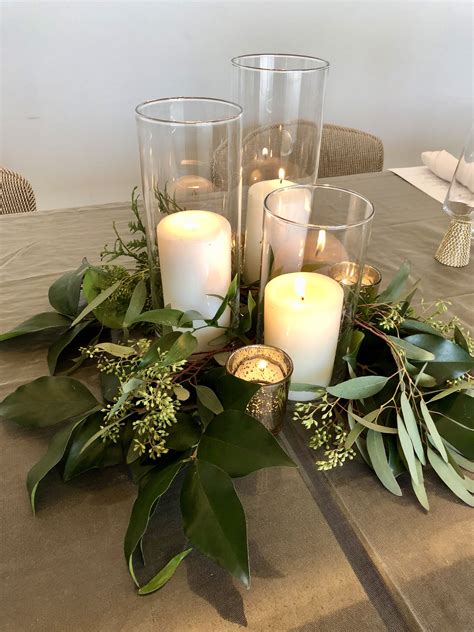 This pillar candle trio, gold mercury glass votives, and various kinds of greenery make up this ...