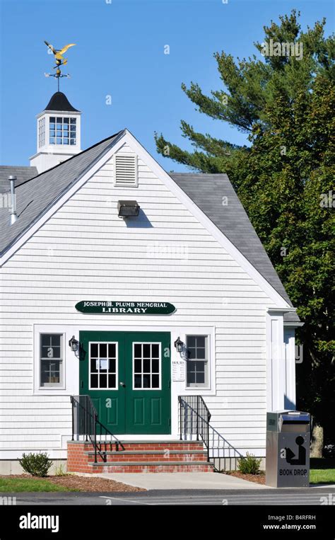 Front exterior of small old white clapboard New England library with book drop box, green double ...