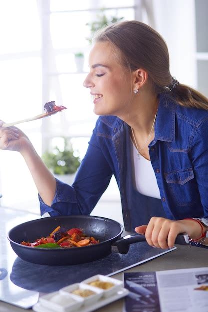 Premium Photo | Young woman cooking healthy food holding a pan with ...