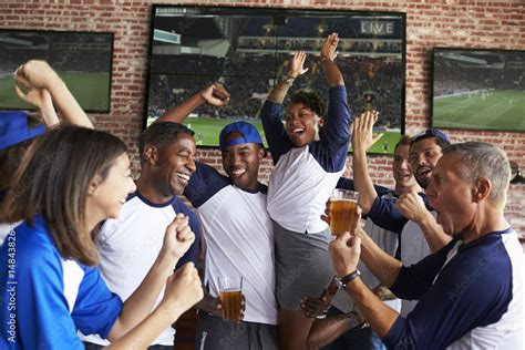 Friends Watching Game In Sports Bar On Screens Celebrating Stock Photo ...