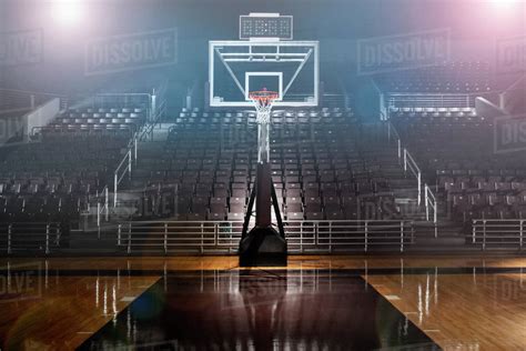 Empty basketball arena with dramatic lighting, view from free throw line in front of goal on the ...