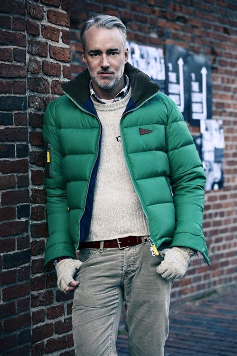 Michael Bastian wearing Green Puffer Jacket, Beige Crew-neck Sweater, White and Red and Navy ...