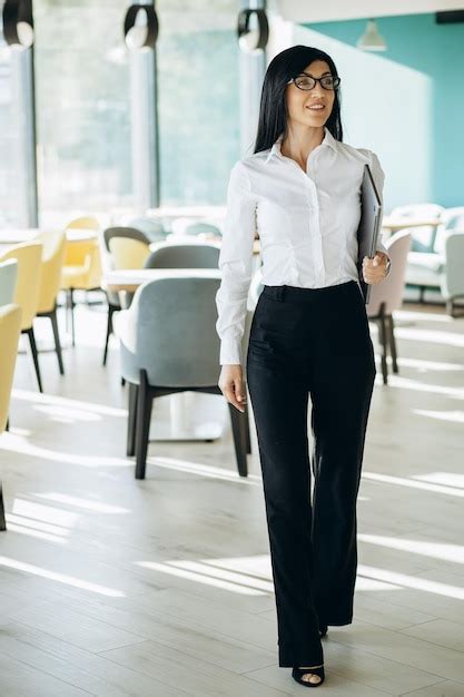 Premium Photo | Attractive business woman in formal wear standing in office and holding laptop