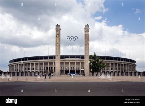 View of the Olympic Stadium in Berlin with main entrance and Olympic Rings against cloudy sky ...