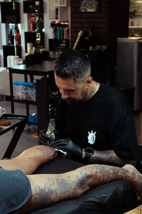 A man getting his tattoo done in a tattoo shop · Free Stock Photo