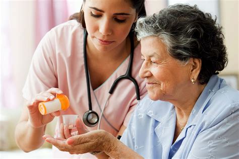 Hispanic nurse helping senior woman with medication - Preferred Home Health Care & Nursing Services