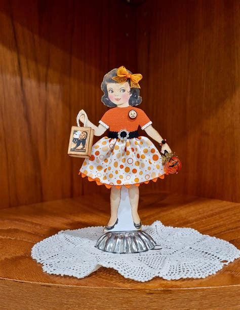 a figurine is sitting on top of a doily in front of a wood paneled wall