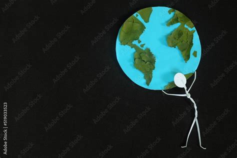 Human stick figure man carrying the earth on his shoulders on dark black background. Save planet ...