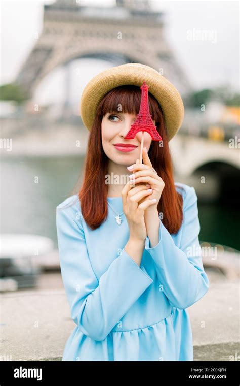 Beautiful woman with sweet candy lollipop posing on the background of Eiffel tower and Seine ...