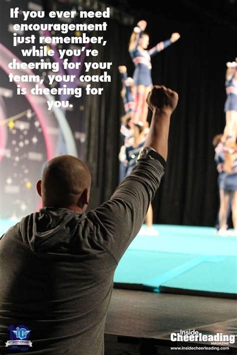 a man standing on top of a stage holding his arms up in the air with two cheerleaders behind him