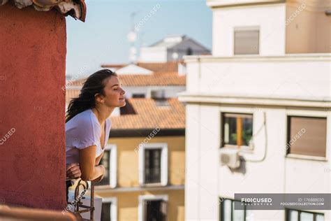 Side view of brunette girl leaning out of balcony and enjoying new day — facades, architecture ...