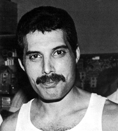 black and white photograph of a man with a moustache on his face wearing a tank top