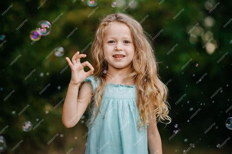 Premium Photo | Portrait little blonde child girl show finger okay symbol sign language on green ...