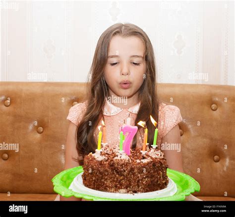 little girl 7 years old blowing out the candles on a birthday cake Stock Photo - Alamy