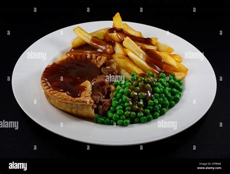 Close up of Steak Pie and chips with peas and gravy. A traditional ...