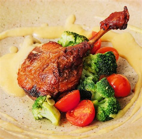 Premium Photo | Confit duck leg with broccoli and tomatoes