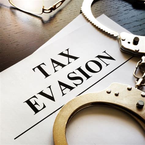 tax evasion written on a piece of paper next to a pair of handcuffs and eyeglasses