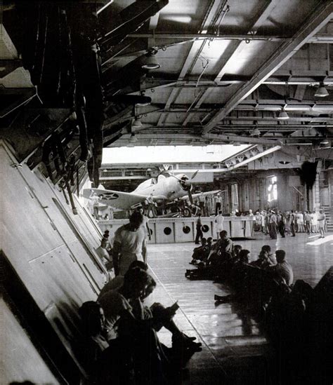 Inside Hangar Deck of USS Enterprise (CV6), crew relax under spare propellers as elevator lifts ...