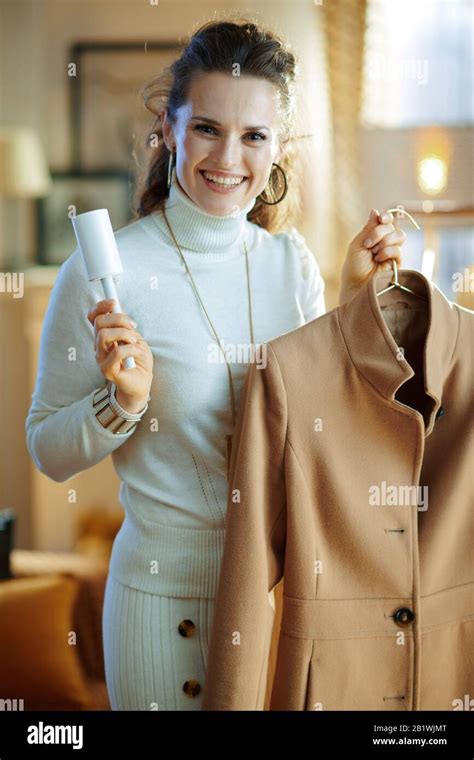 Preparing for cold season. smiling modern 40 years old housewife in white sweater and skirt ...