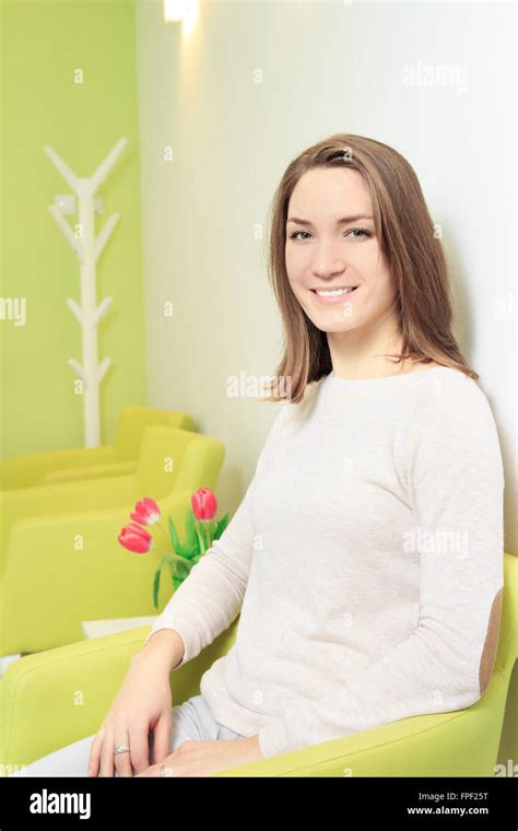 Young woman sitting and smiling in waiting room Stock Photo - Alamy