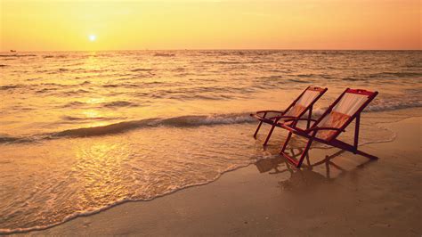 Sunset Serenity: HD Wallpaper of Beach Chairs by the Ocean Horizon