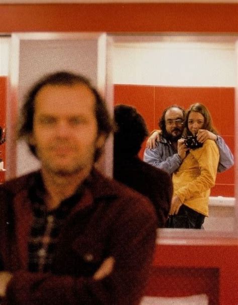 a man taking a selfie in front of a mirror with two women and a man