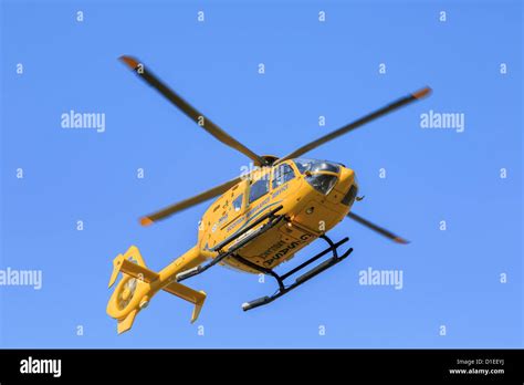 Yellow Scottish Air Ambulance Service Helicopter flying overhead from a rescue mission seen from ...