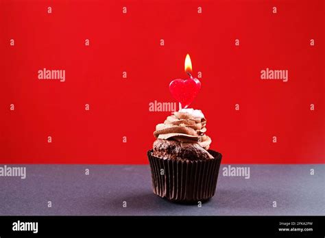 Delicious chocolate single buttercup cupcake, burning heart shape festive candles, sugar topping ...