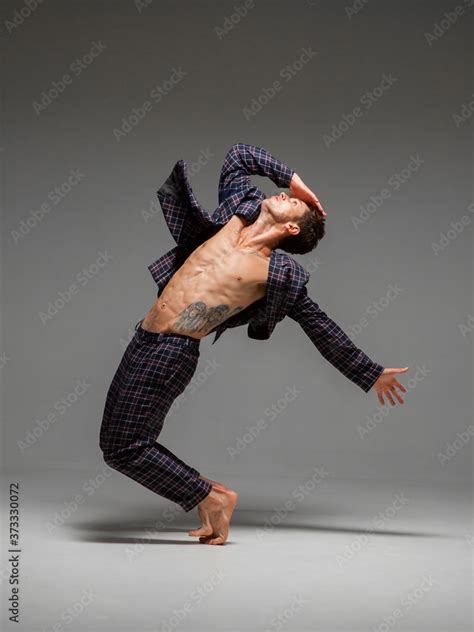 Handsome young guy dancer in suit and barefoot dancing expressive dance ...