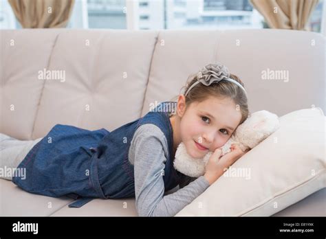 Little girl lying on the couch with teddy Stock Photo - Alamy