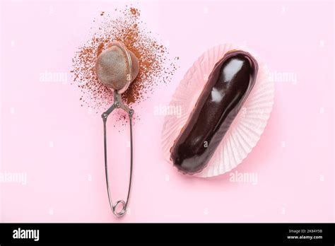 Tasty chocolate eclair and sieve with cocoa powder on pink background Stock Photo - Alamy
