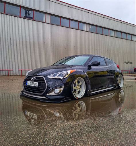 a black car parked in front of a building on a wet parking lot next to ...