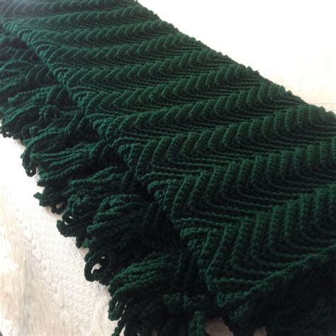 a green knitted blanket laying on top of a bed