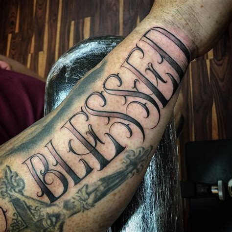 Lettering tattoo saying "Blessed" on the right forearm.