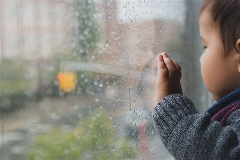 "Baby Looking Out Window On Rainy Day" by Stocksy Contributor "Lauren Lee" - Stocksy