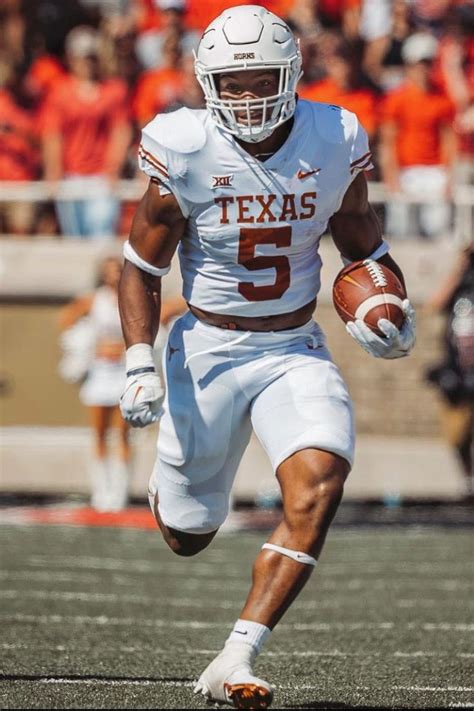 a football player running with the ball in his hand and people watching ...